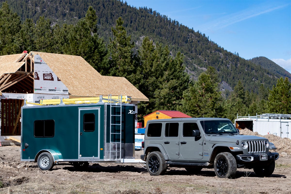 Gray Jeep Hauling Enclosed Cargo 5/6 Wide Trailer Behind Construction Site