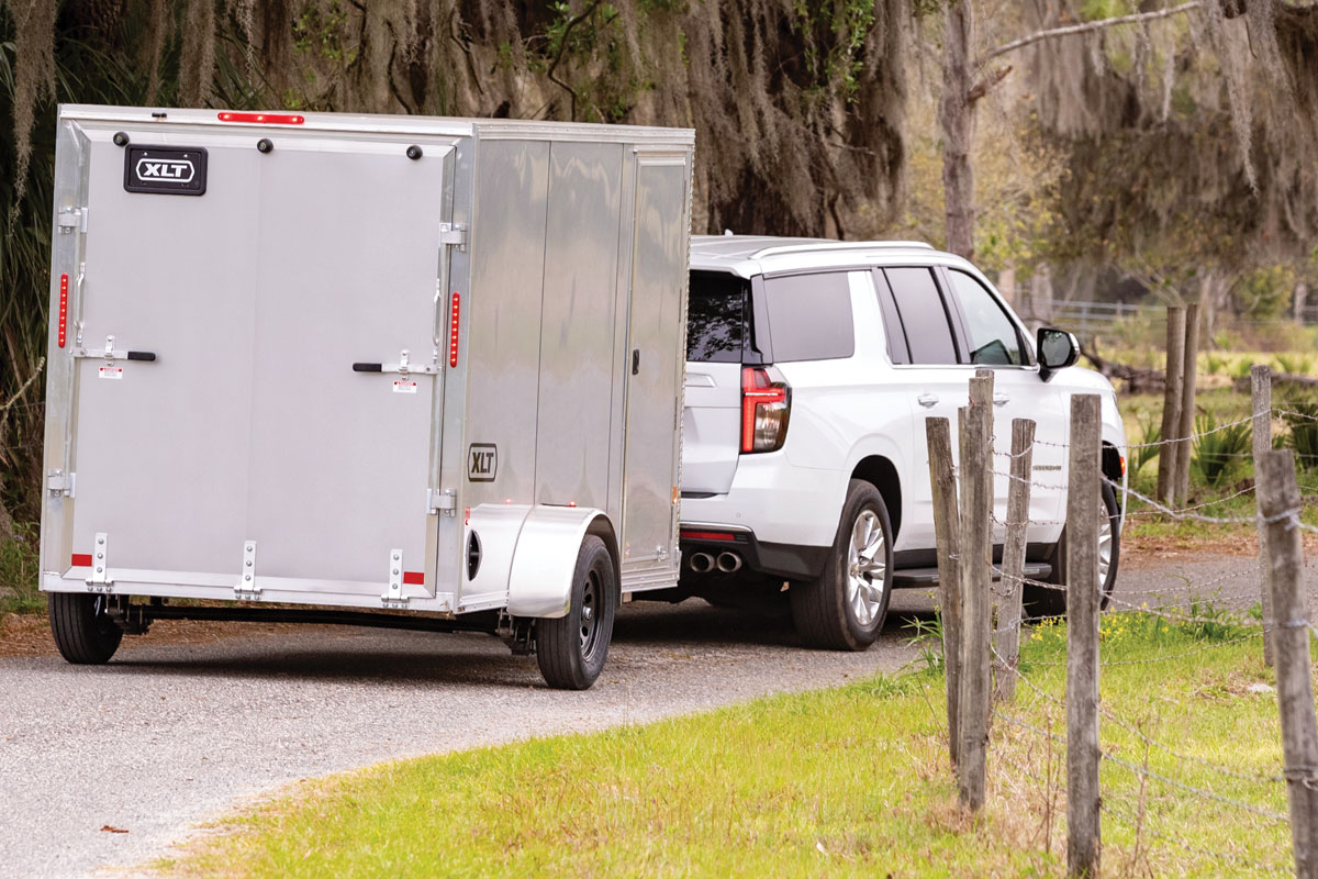 Rear view of a 6 wide xlt pro gray trailer driving down the road