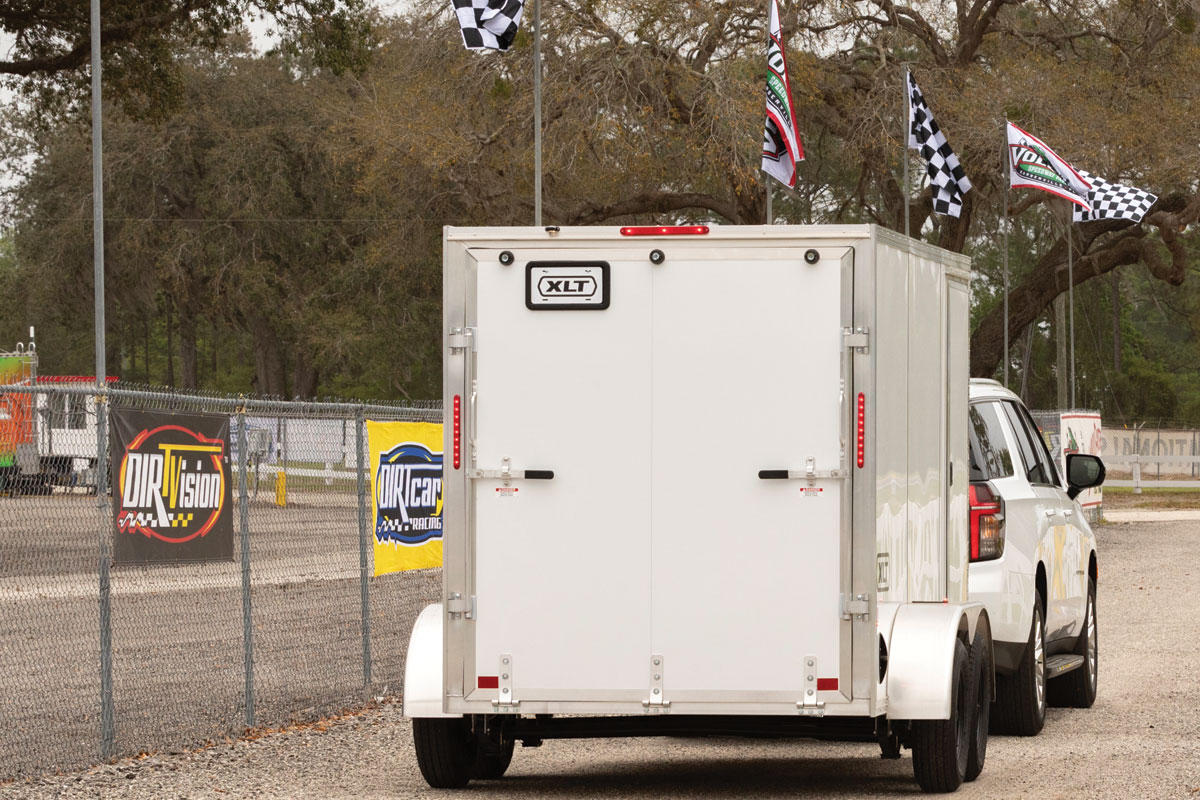 White SUX towing 7 Wide XLT Pro trailer down dirt road